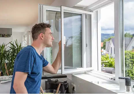 Mann öffnet ein maßgefertigtes Fliegengitter-Drehfenster am Küchenfenster
